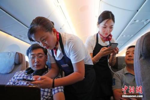 資料圖：乘務(wù)員們在客艙內(nèi)為旅客調(diào)試機(jī)上上網(wǎng)功能。<a target='_blank' ><p  align=